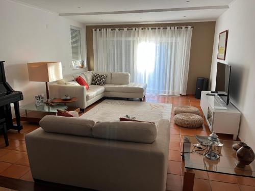 a living room with a couch and a television at Vivenda espaçosa com jardim e churrasqueira in Alcabideche