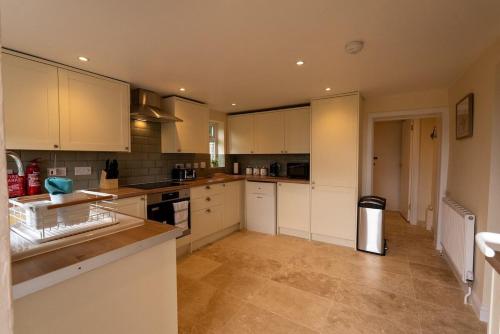 a kitchen with white cabinets and a counter top at Rose cottage in Bransgore