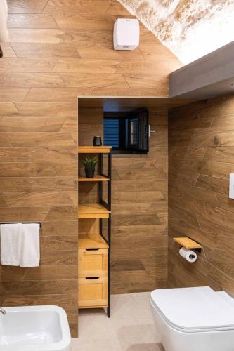 a bathroom with a white toilet and wooden walls at Castel Manfredi Apartments in Manfredonia