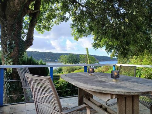 a wooden table and chairs on a deck with a view at An Koad - Cabane au bord de l'eau in Plougastel-Daoulas
