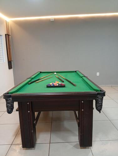 a green pool table with two cuesticks on it at Espaço Quintal do Encontro in Ponta Porã