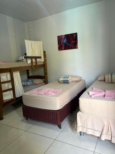 two twin beds in a room with a table at POUSADA EIRU in Bonito