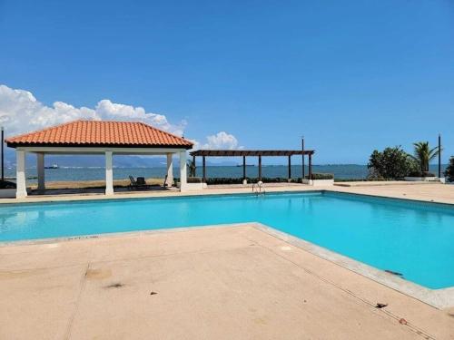 einen Pool mit Pavillon am Meer in der Unterkunft CASA PORS Beach Front Apartment with security, pool &jacuzzi in Portmore