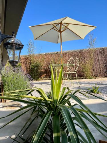 a patio with a chair and an umbrella and a plant at Le Pré de la Mer Suite & SPA Privatif in Querqueville