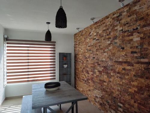 a room with a brick wall and a wooden table at Hermosa Residencia en Oaxtepec in Oaxtepec