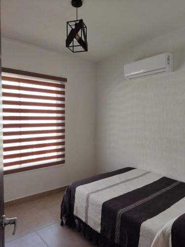 a white bedroom with a bed and a window at Hermosa Residencia en Oaxtepec in Oaxtepec