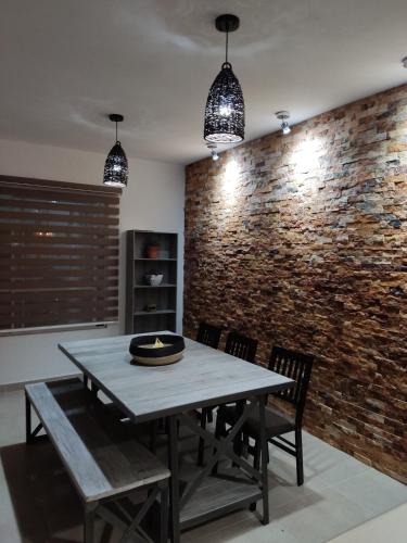 a dining room with a table and chairs and a brick wall at Hermosa Residencia en Oaxtepec in Oaxtepec