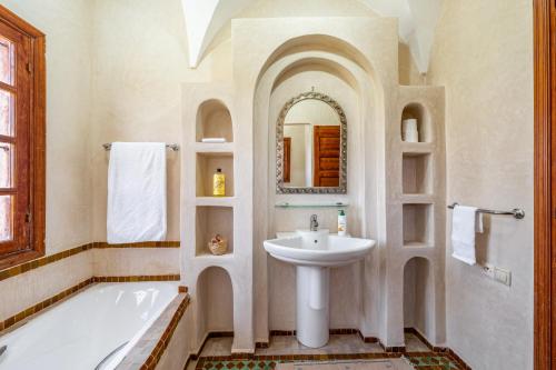 a white bathroom with a sink and a bath tub at Riad du Bab atlas in Marrakesh
