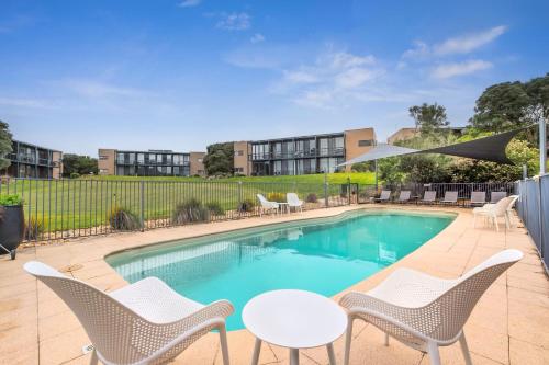a swimming pool with white chairs and a table and chairs at 1BR Apartment 43 sleeps 5,Golf,Beach,Hot Springs in Fingal