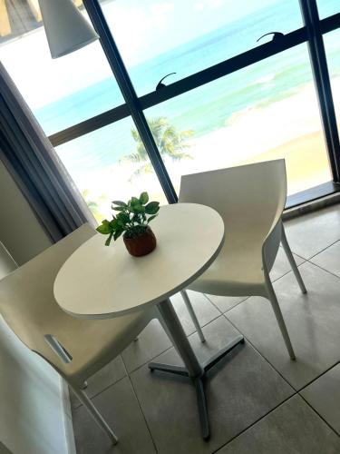 a table and two chairs with a plant on it at Refúgio do Mar 705 - Condomínio Edifício Ritz Suítes Home Service in Maceió