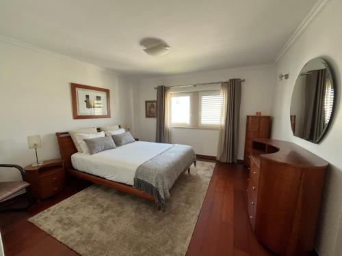 a bedroom with a bed and a dresser and a window at Vivenda espaçosa com jardim e churrasqueira in Alcabideche
