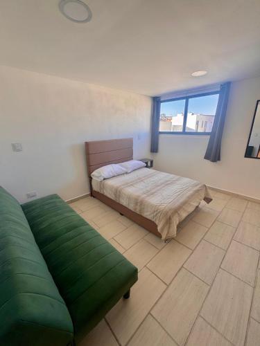 a bedroom with a bed and a couch and a window at Casa en Fraccionamiento Privado con alberca in Cuautlancingo