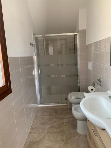 a bathroom with a shower and a toilet and a sink at CASA VACANZE gli ULIVI 23 in Sìnnai