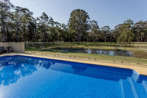 a swimming pool with a view of a field and trees at Chez Vous Villas Pokolbin in Pokolbin