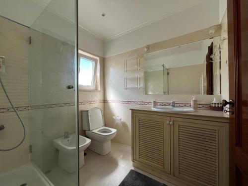 a bathroom with a toilet and a sink and a shower at Vivenda espaçosa com jardim e churrasqueira in Alcabideche