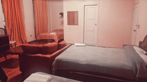 a hotel room with two beds and a chair and a window at Hotel Luis cordero centro historico cuenca in Cuenca