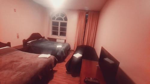 a bedroom with two beds and a window at Hotel Luis cordero centro historico cuenca in Cuenca