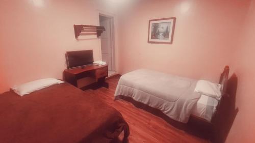 a hotel room with two beds and a television at Hotel Luis cordero centro historico cuenca in Cuenca