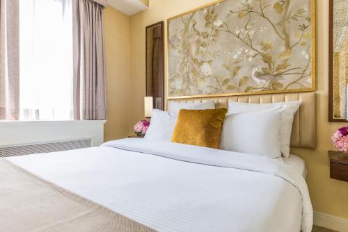 a bedroom with a large white bed with a painting on the wall at Warwick Allerton Chicago in Chicago
