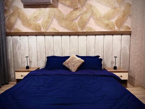 a bedroom with a blue bed with two night stands at Loft Apartments in Duhok