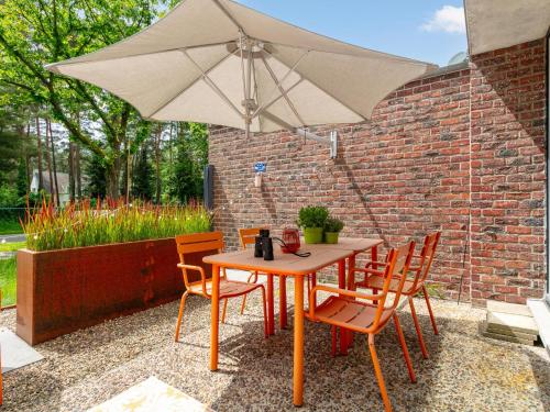 a wooden table with chairs and an umbrella at Maison Clement in Maasmechelen