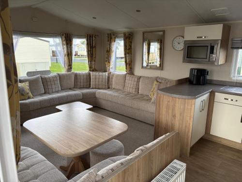 una sala de estar con sofá y mesa en una caravana en Our Happy Place, en Kilkeel