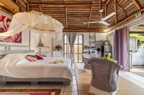a bedroom with a large bed and two chairs at Anapa Beach House in Temae