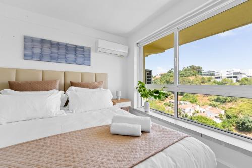 a bedroom with a large bed and a large window at MBird 19 Estoril Apartments in Estoril