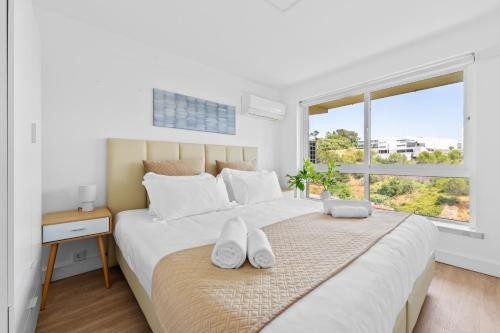 ein weißes Schlafzimmer mit einem großen Bett und einem Fenster in der Unterkunft MBird 19 Estoril Apartments in Estoril