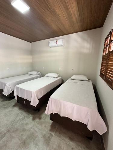 a room with three beds and a window at Pousada Canta Galo in Goiás