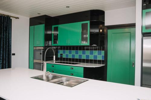 a kitchen with green cabinets and a sink at Saltwood Peterborough in Peterborough