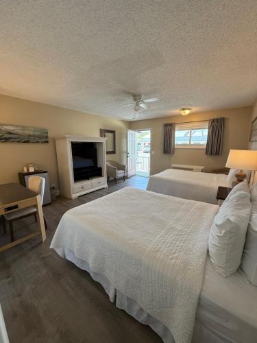 a hotel room with two beds and a flat screen tv at Point Pleasant Manor in Point Pleasant Beach