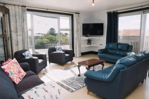 a living room with a blue couch and chairs at Saltwood Peterborough in Peterborough