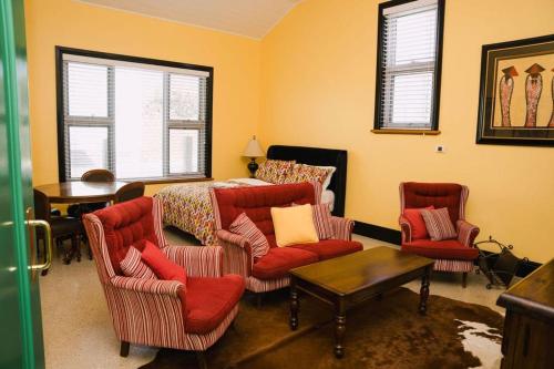 a living room with red chairs and a bed at Saltwood Peterborough in Peterborough