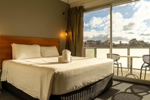 a bedroom with a bed and a balcony with a view at Cosmopolitan Hotel and Apartments in Melbourne