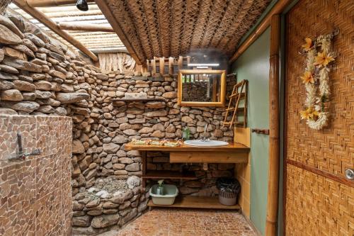 a bathroom with a stone wall with a sink in it at Anapa Beach House in Temae