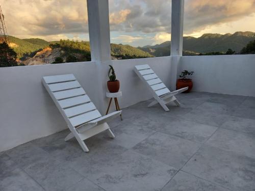 Duas cadeiras brancas numa varanda com vista para as montanhas em Hostal De María em San Cristóbal de Las Casas