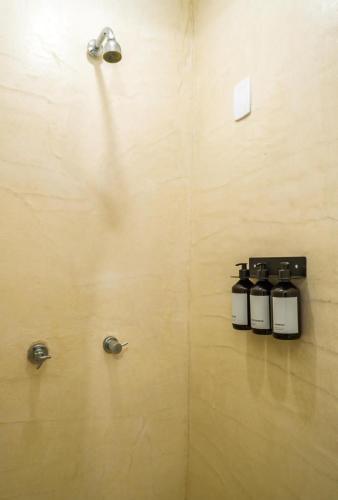 three bottles on a wall in a bathroom at Estúdio Estiloso em Morro de São Paulo Perto Praia in Morro de São Paulo