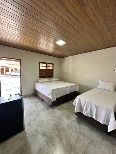 a bedroom with two beds and a wooden ceiling at Pousada Canta Galo in Goiás