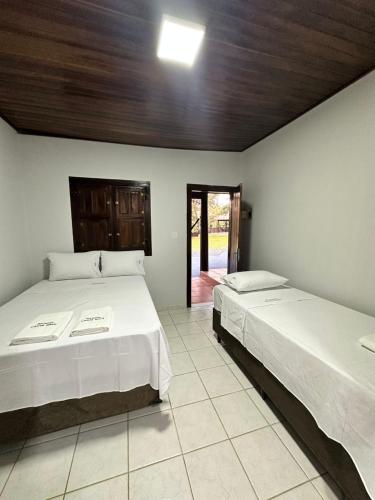 a bedroom with two beds and a door to a patio at Pousada Canta Galo in Goiás