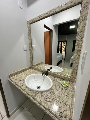 a bathroom counter with a sink and a mirror at Pousada Canta Galo in Goiás