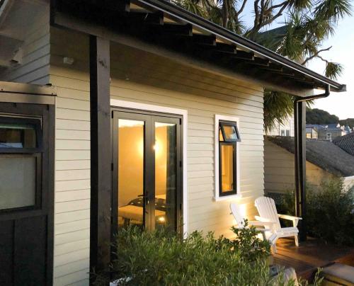 a small house with a porch and two white chairs at Wellington Inner City Hideaway-Walk to Everything! in Wellington