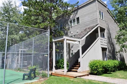 a house with a fence and a tennis court at RMR: Mountain Maple 4 Condo in The Aspens in Wilson