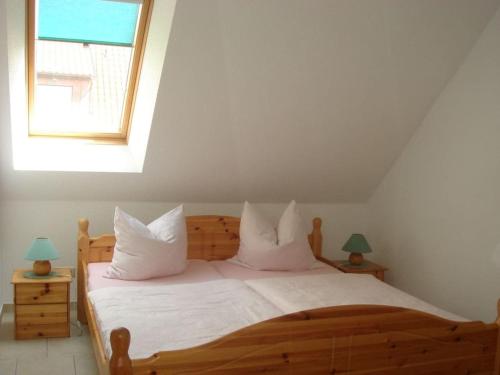 1 dormitorio con cama de madera con almohadas blancas y ventana en Holiday home in Waren with swimming pool, en Waren