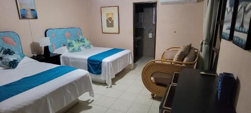 a hotel room with two beds and a chair at Suites Atlas - Ocean Front in Bucerías