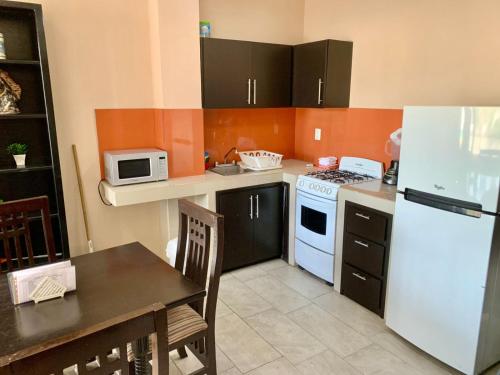 a kitchen with a white refrigerator and a table at Suites Atlas - Ocean Front in Bucerías