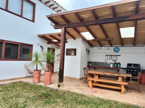 Un patio con una pérgola de madera y una mesa de madera. en Exclusiva Casa BBQ Parking & Confort, en Villa de Leyva