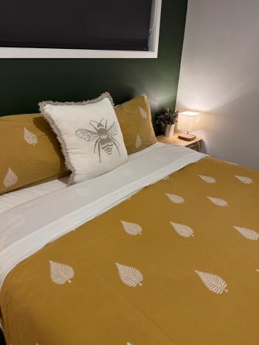 a bed with a yellow comforter and a pillow at The Kingfisher cabin in Tauranga