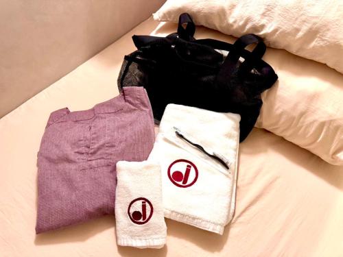 a bed with clothes and a bag on it at HOTEL minimumms女性専用カプセルホテルWomen only hotel in Naha