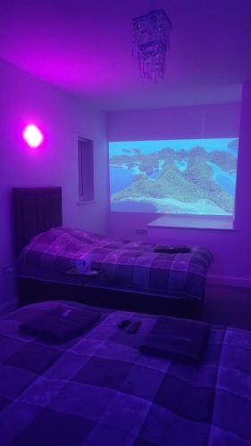 a bedroom with a large screen with purple lights at Cedar Townhouse in Wibsey